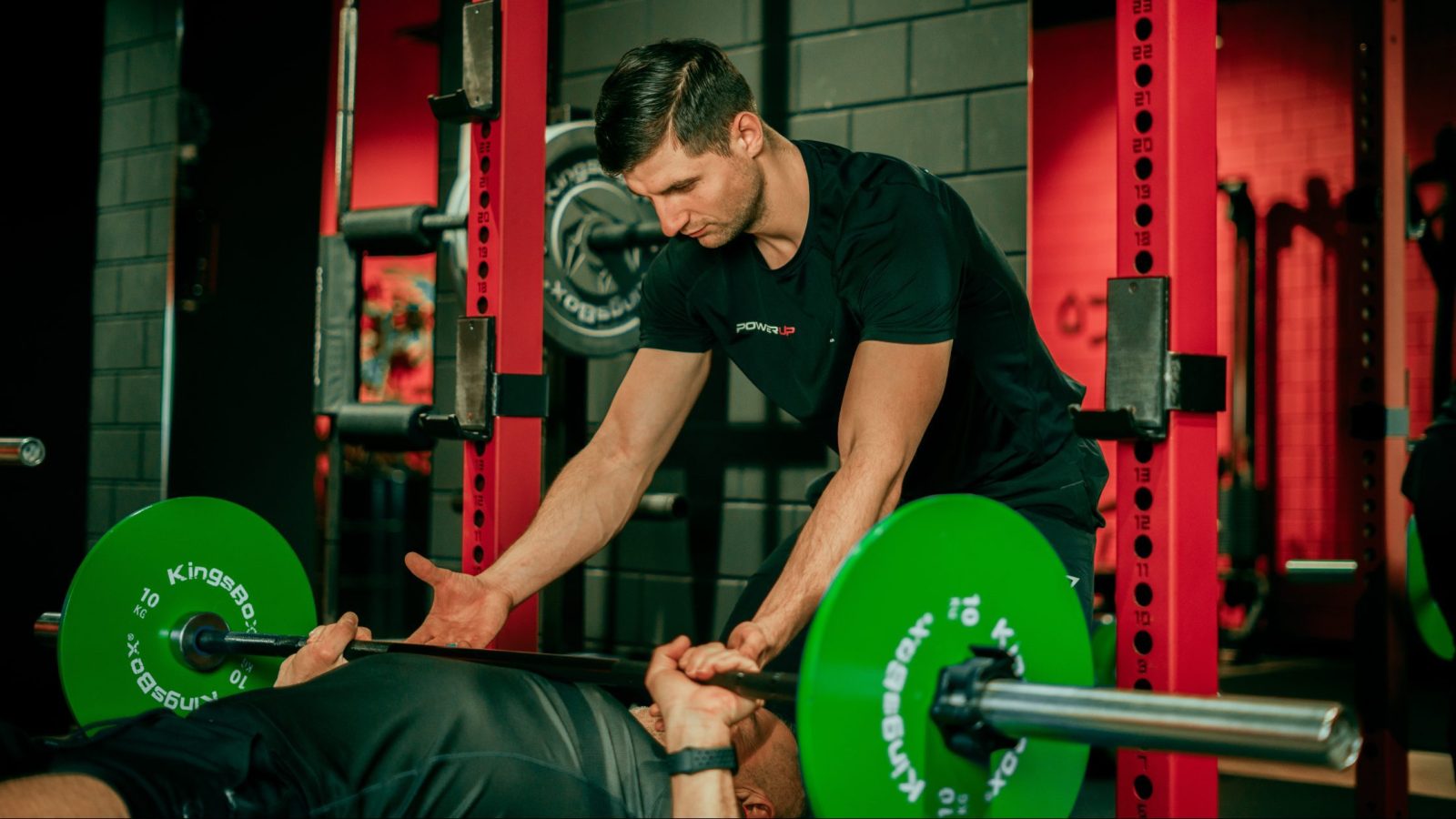 personal trainer supporting trainee with bench press